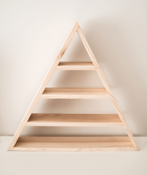 Zdjęcie produktowe przedstawiającą półkę - model triangle - czyli półkę trójkątną. Półka ze zdjęcia jest wykonana z drewna, jest to lity jesion w jasnym odcieniu. Półka ma trójkątny kształt, i trzy piętra (cztery, jeśli liczyć również dolną podstawę).